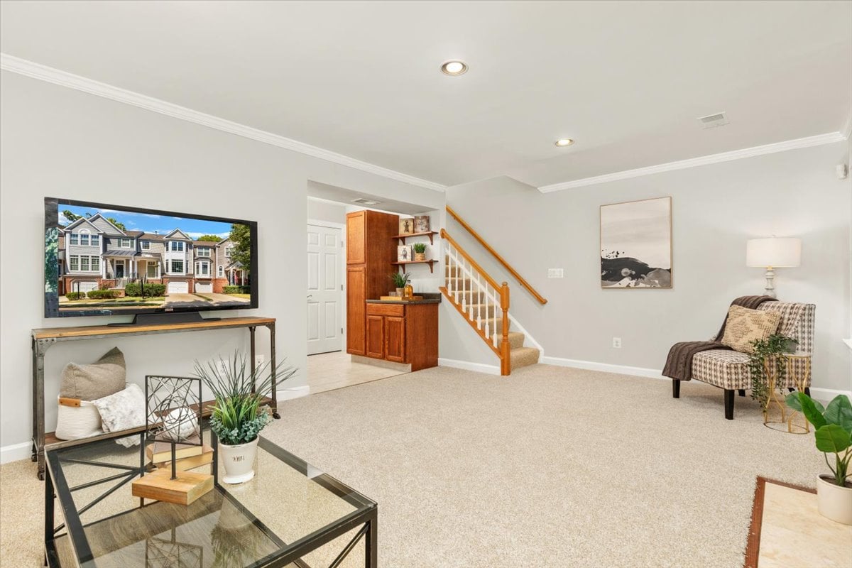 Carpeted living area with a staircase, wood cabinetry, and a TV on a console.