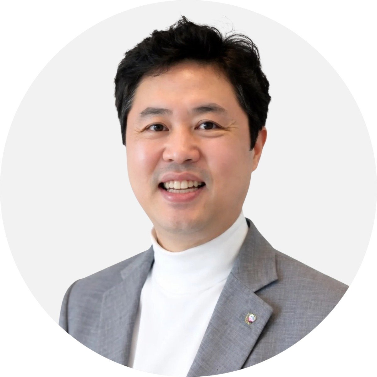 Michael Min, smiling in a gray suit and white turtleneck.