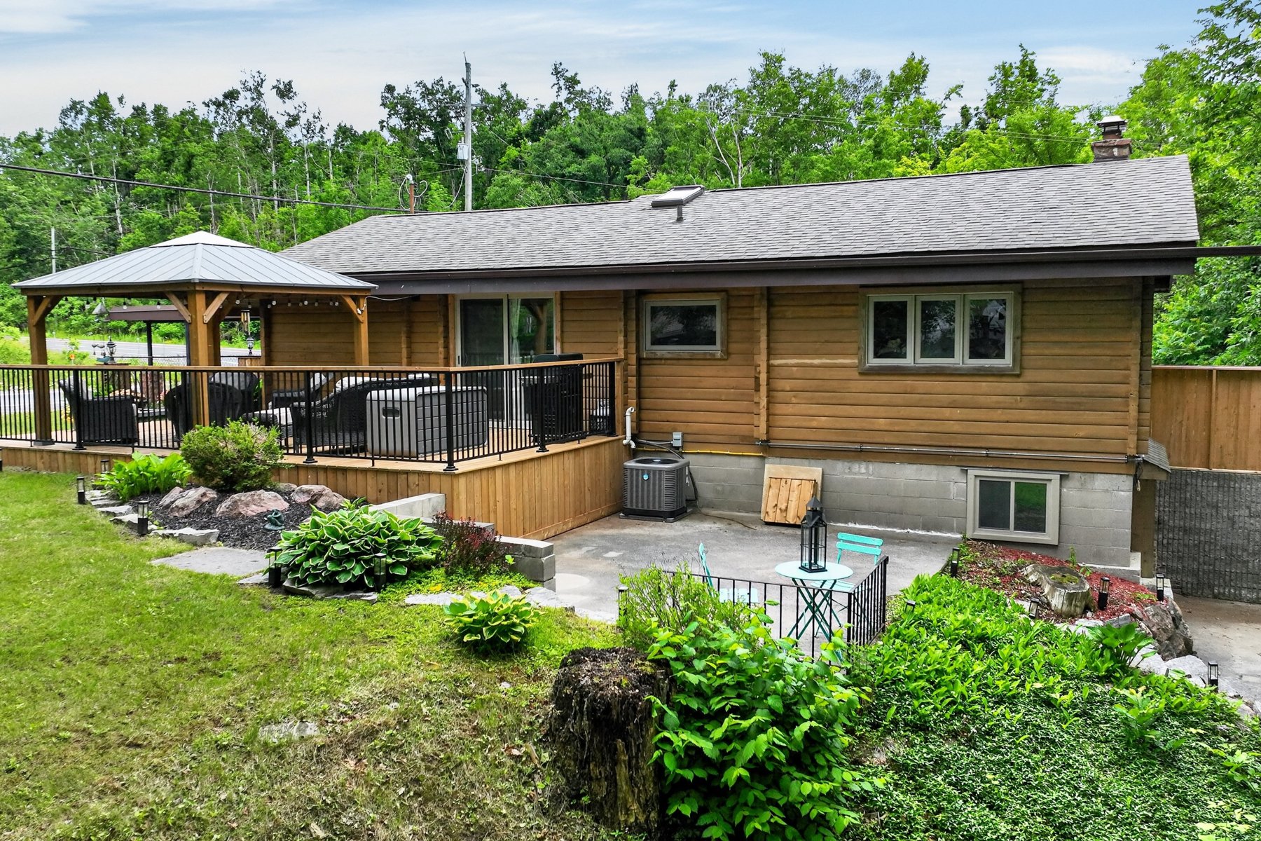 Wood-sided house with a raised deck and gazebo overlooking a landscaped yard.