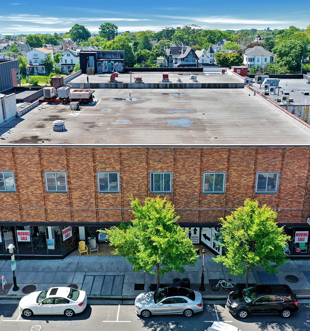 614 Cookman Avenue, a red-brick commercial building with a broad flat roof and storefronts along a tree-lined street.
