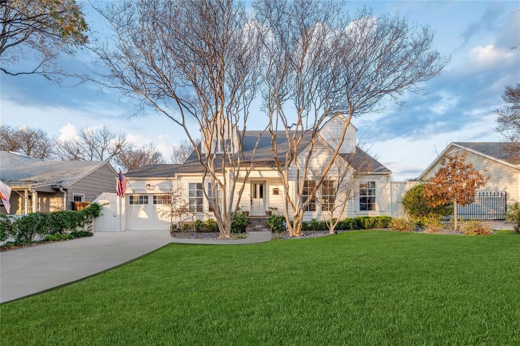 White house with a broad front lawn, driveway, and leafless trees.
