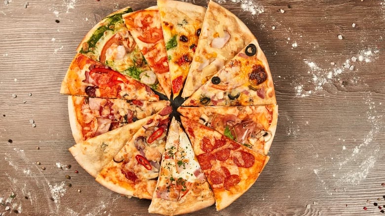 A colorful display of various pizza styles laid out on wooden boards, showing Neapolitan, New York, Sicilian, and California-style slices