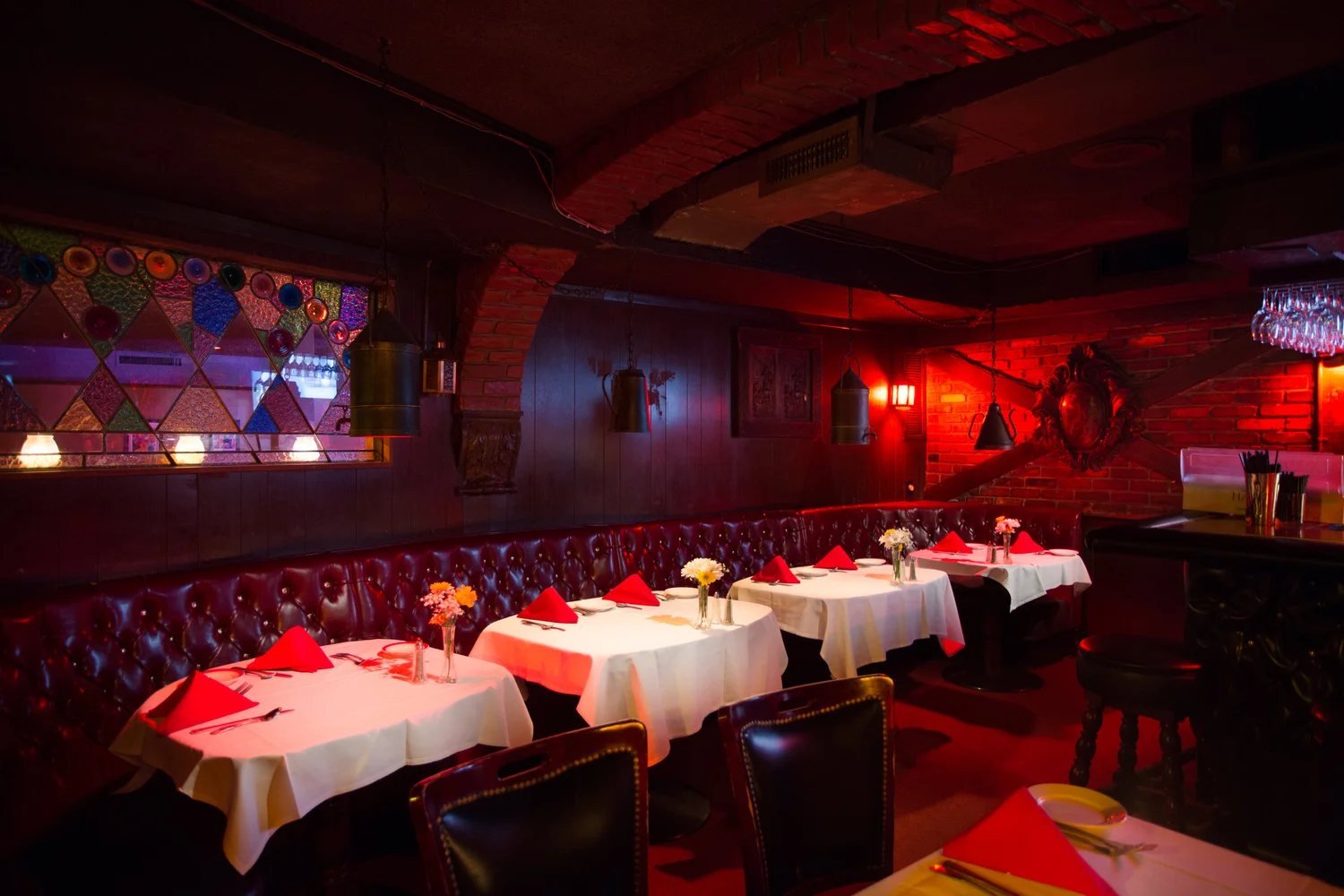 La Cave's underground dining room, with red booths, white tablecloths and low red lighting.