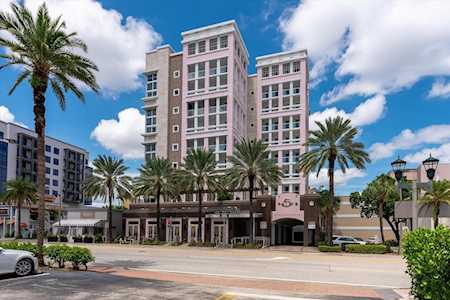 Condominium building with a pink central facade, white balconies, and palm trees along the street.