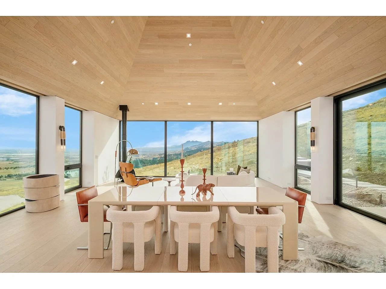 Dining room with a high wood ceiling, large table, and expansive mountain-view windows.