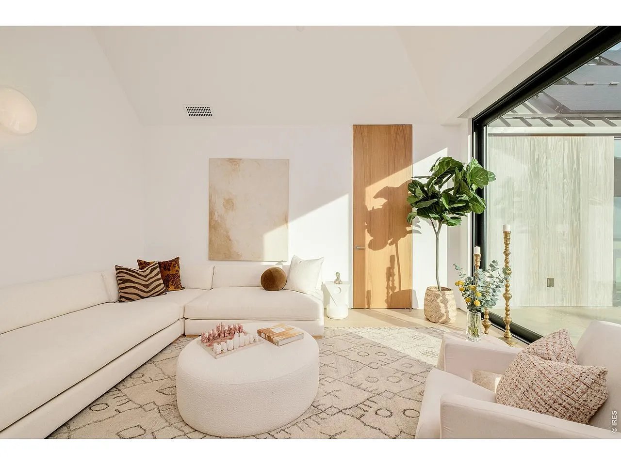 Bright living room with a white sectional, round coffee table, patterned rug, and large patio windows.