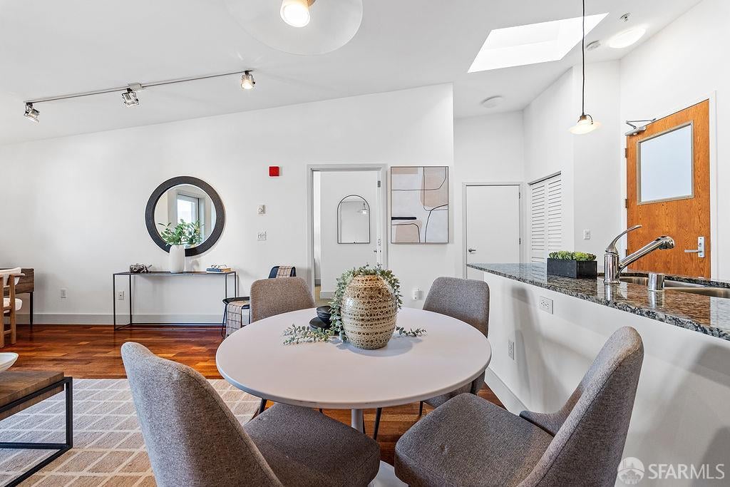 Dining area with a round table, upholstered chairs, hardwood floors, and a skylight.