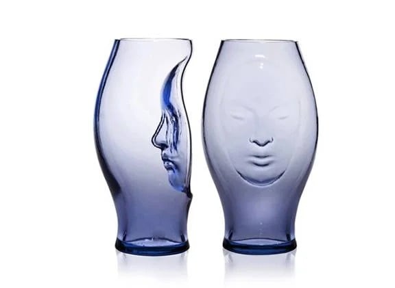 Two blue glass vessels feature sculpted faces in profile and from the front.