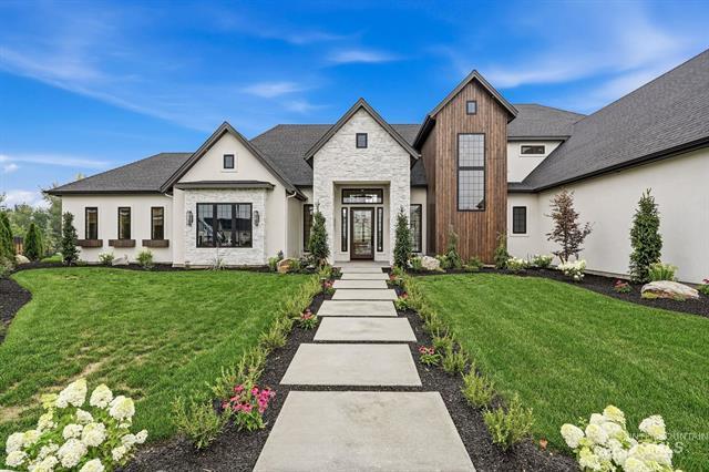 Modern home with a wood-accented entry tower and a concrete walkway through landscaped lawns.
