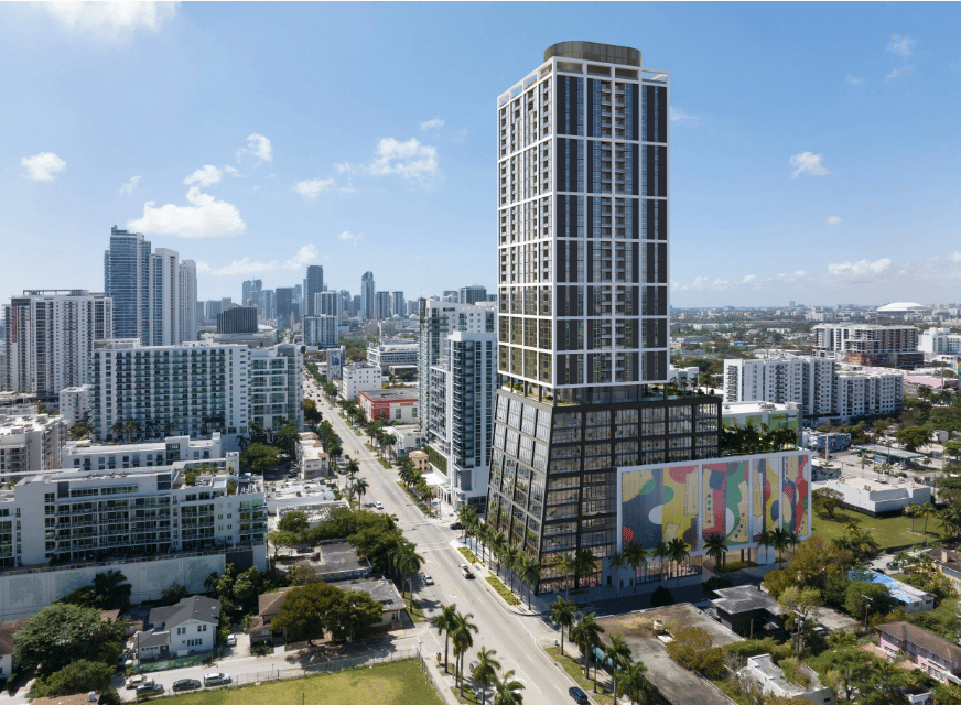 Modern residential tower with a colorful mural at its base, rising above city streets and buildings.