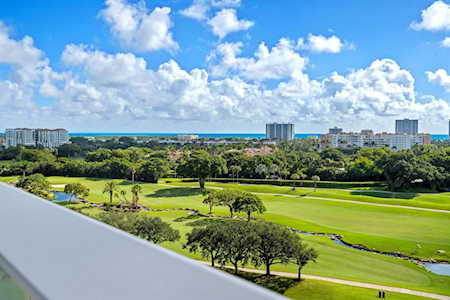 East Boca golf course with a winding water feature, ocean, and distant coastal buildings.