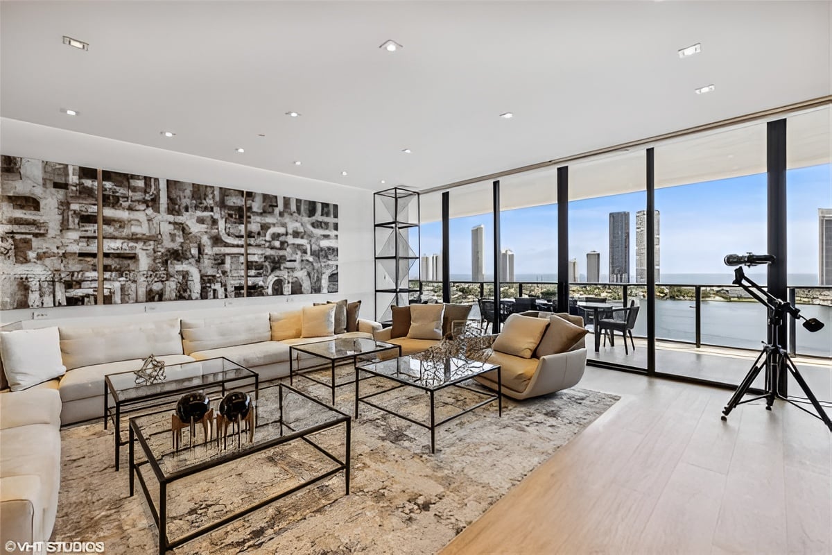Modern living room with floor-to-ceiling windows overlooking the ocean and city skyline.