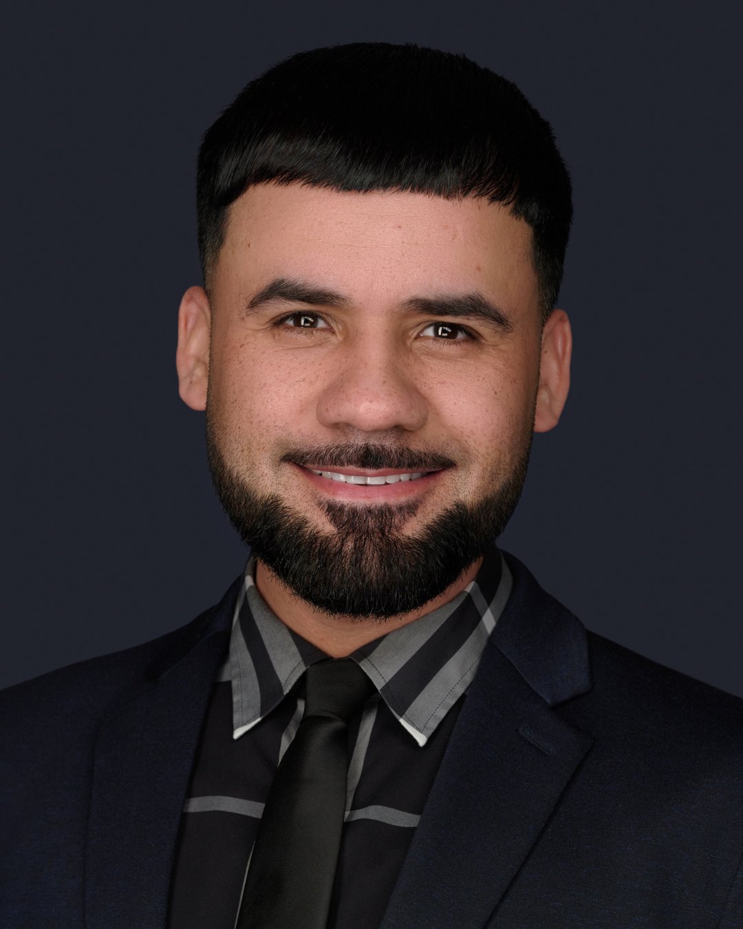 Josue Nieves smiling in a dark suit and patterned shirt.