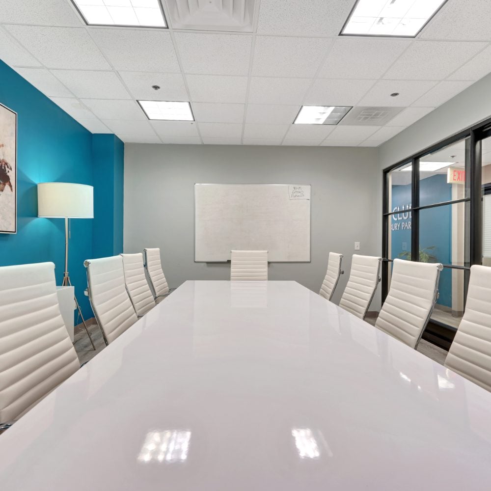 Conference room with a glossy white table, white chairs, and teal accent wall