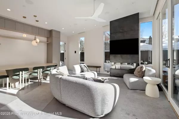 Modern living room with curved white sofas, a black fireplace, and adjoining dining area.