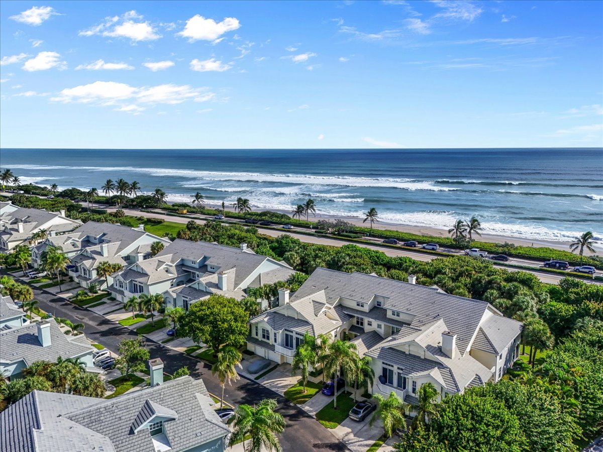 Sea Colony condominiums beside a palm-lined beach and ocean.