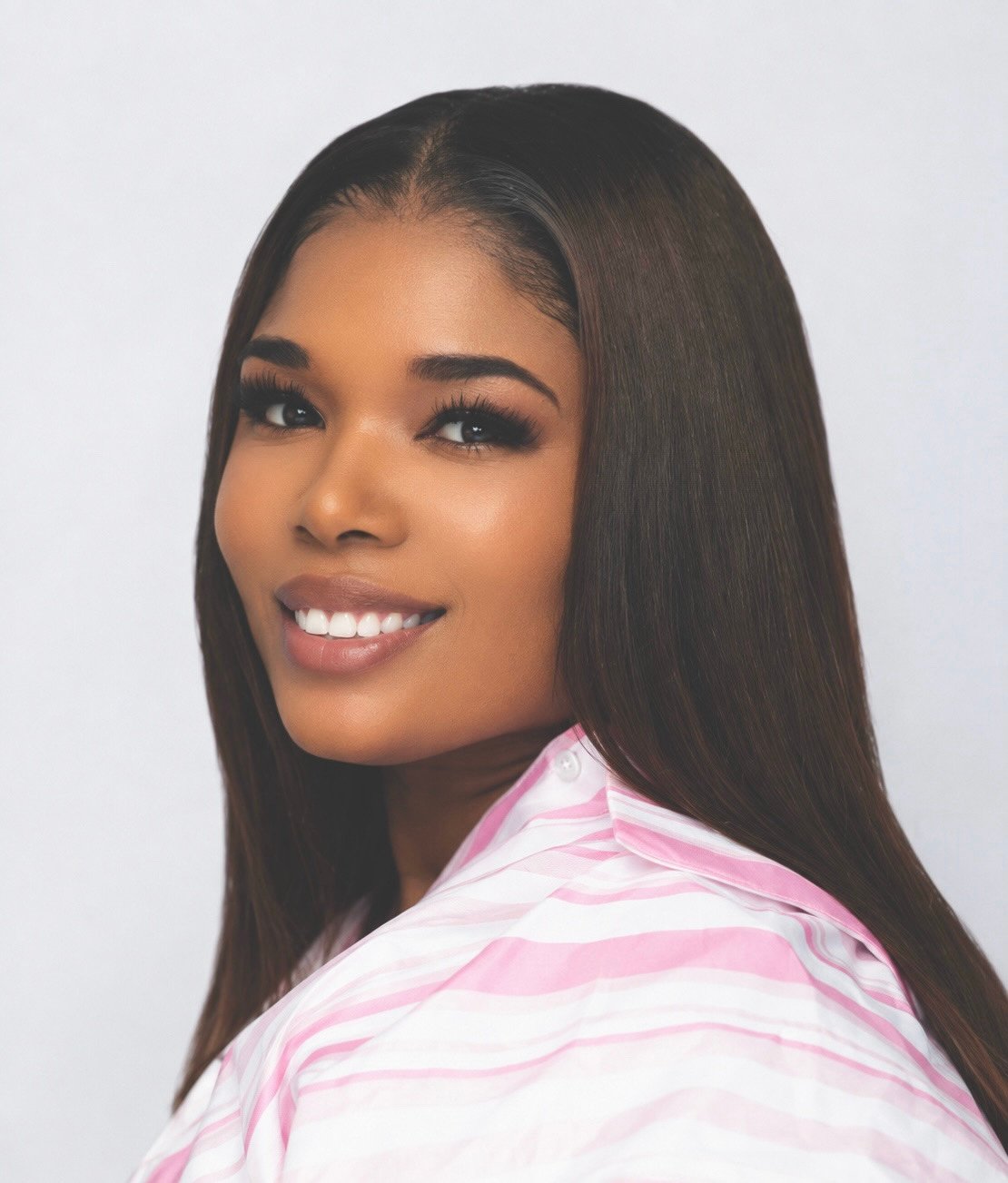 Lynnecia Julien smiling in a pink-and-white striped shirt.