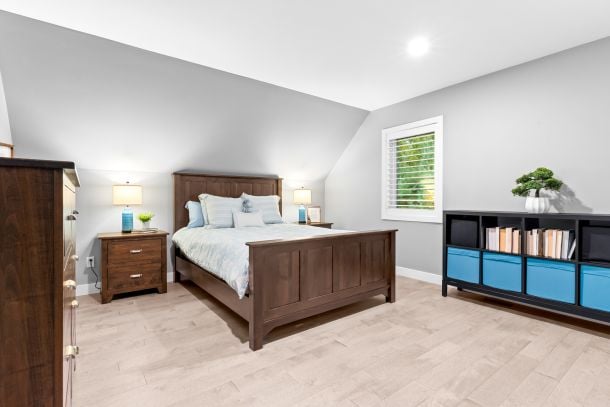 Bedroom with a dark wood bed, pale flooring, and a bookcase with blue storage bins.