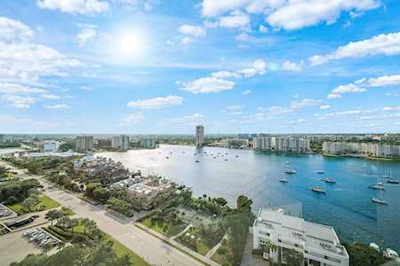Aerial waterfront view with boats, residences and condominium buildings along a broad waterway.