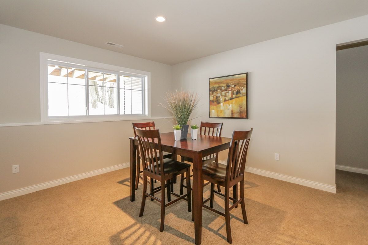 Dining room with a dark wood table and chairs beside a large window.