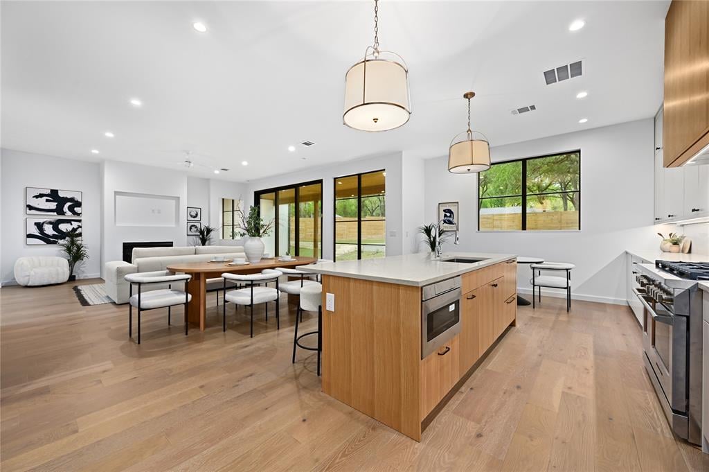 Open-concept living, dining, and kitchen area with wood floors at 2635 Barton Hills Dr, Austin.