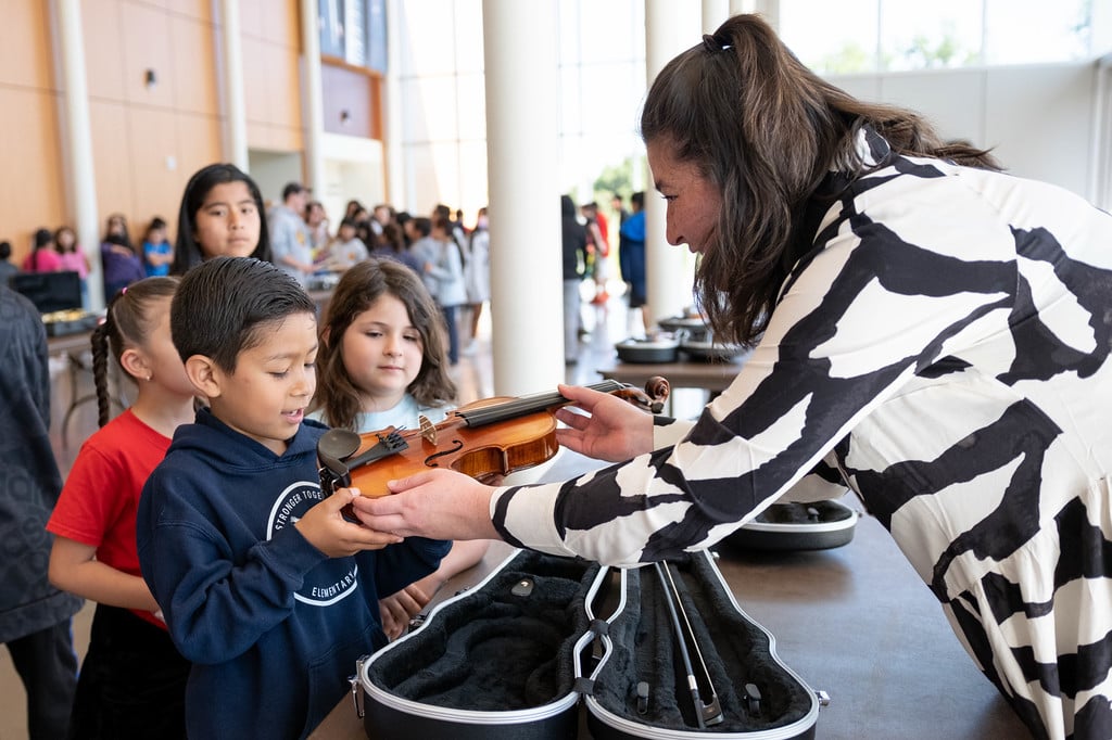 Children examine a violin with an instructor during the Novack Concert for Kids at Napa Valley College Performing Arts Center.