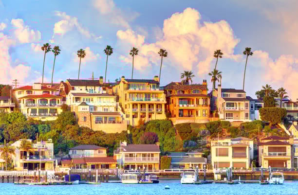 Aerial view of Newport Beach homes along the harbor on a clear California day
