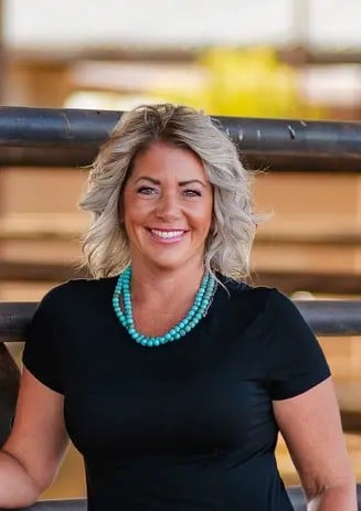 Lindsey Smith smiling in a black top and turquoise necklace.