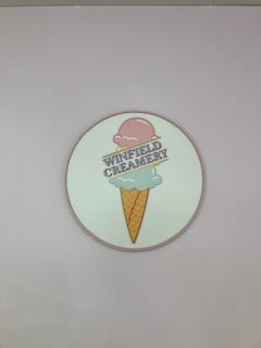 Circular wall handing displaying an ice cream cone with pink and light blue scoops, overlaid with the text "Winfield Creamery."