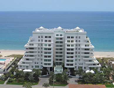 White beachfront condominium with rows of balconies overlooking the beach and ocean.