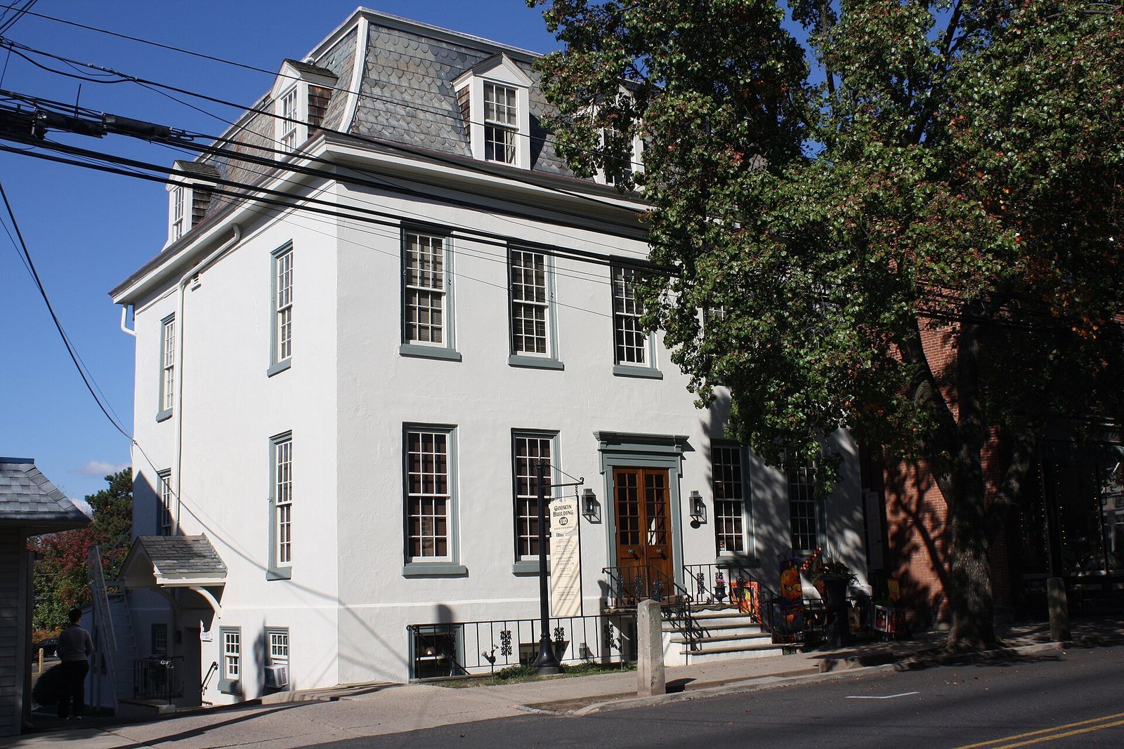White three-story historic Godwin Building on South State Street under a blue sky in Newtown, PA