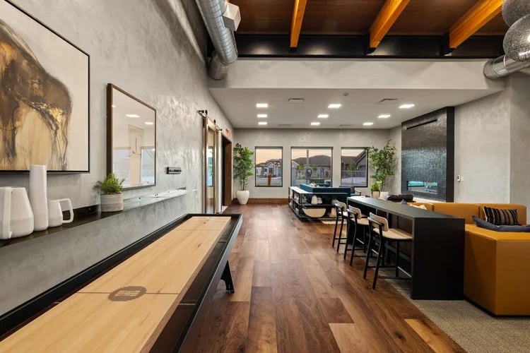 Communal recreation room with a shuffleboard table, bar seating, and lounge area.