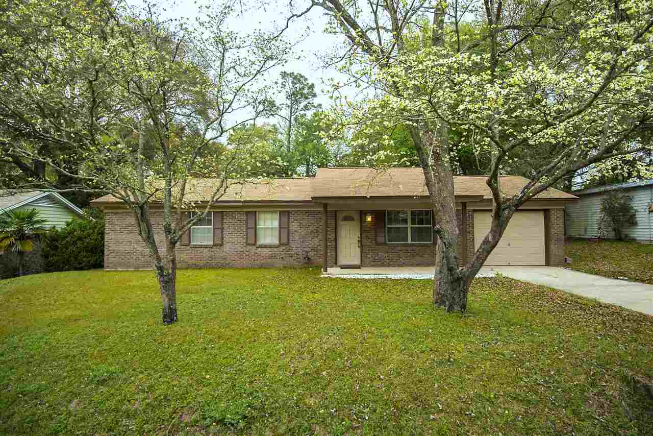 A brick home surrounded by a lush yard and trees, showcasing a serene and inviting outdoor environment.