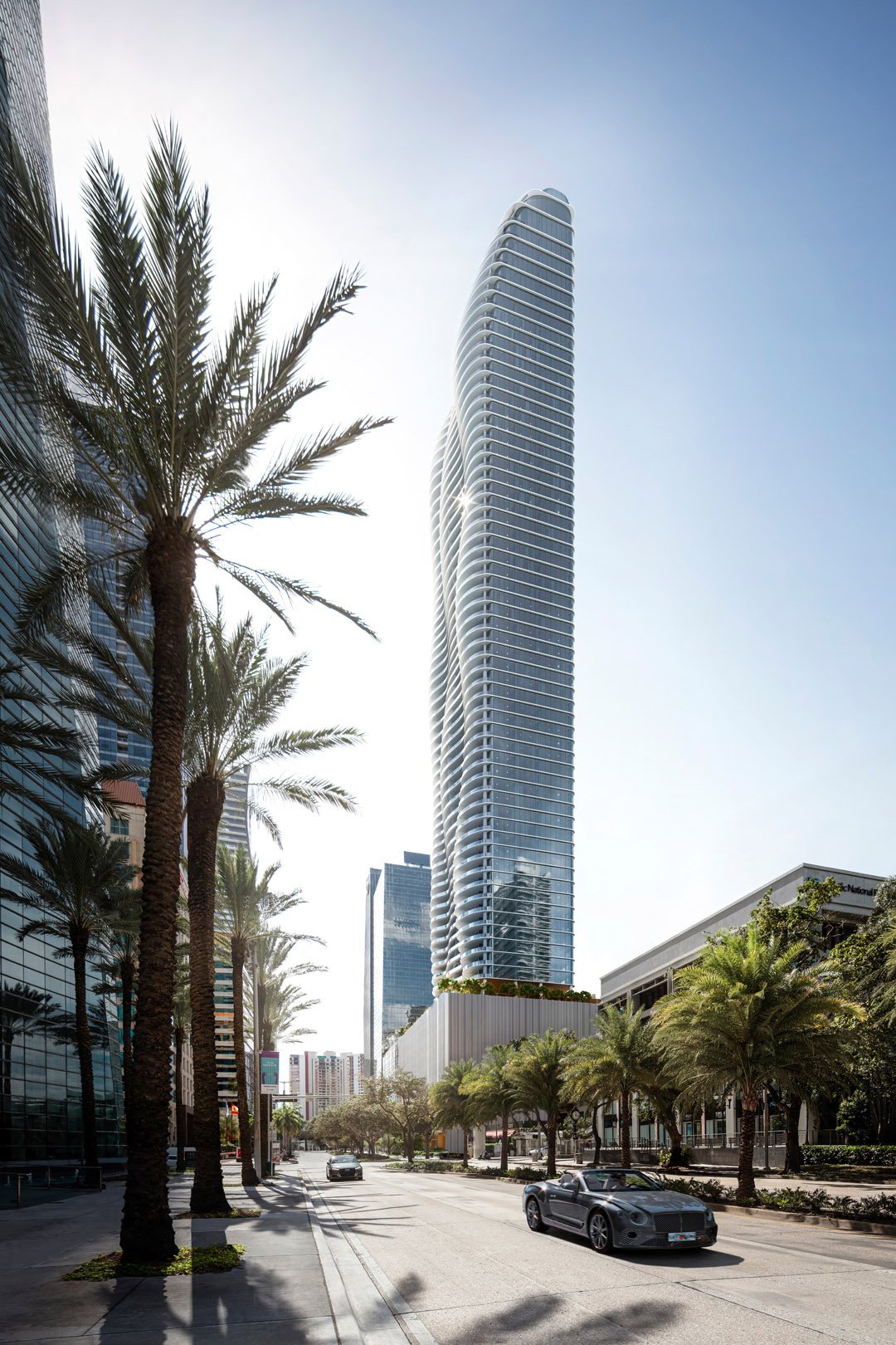 1428 Residences tower with curved balconies above a palm-lined Brickell street.