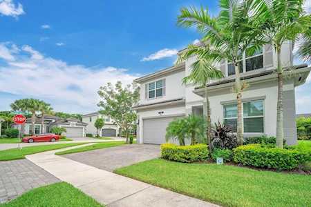 Two-story home with a garage, palm trees, and a landscaped front yard.