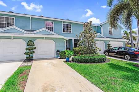 Blue two-story townhouses with attached garages, landscaped lawns, and palm trees.