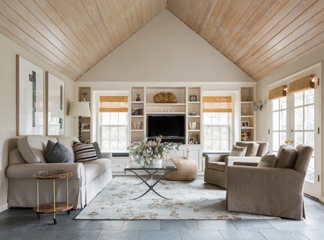 Bright living room with a vaulted, light wood-plank ceiling and built-in shelving.