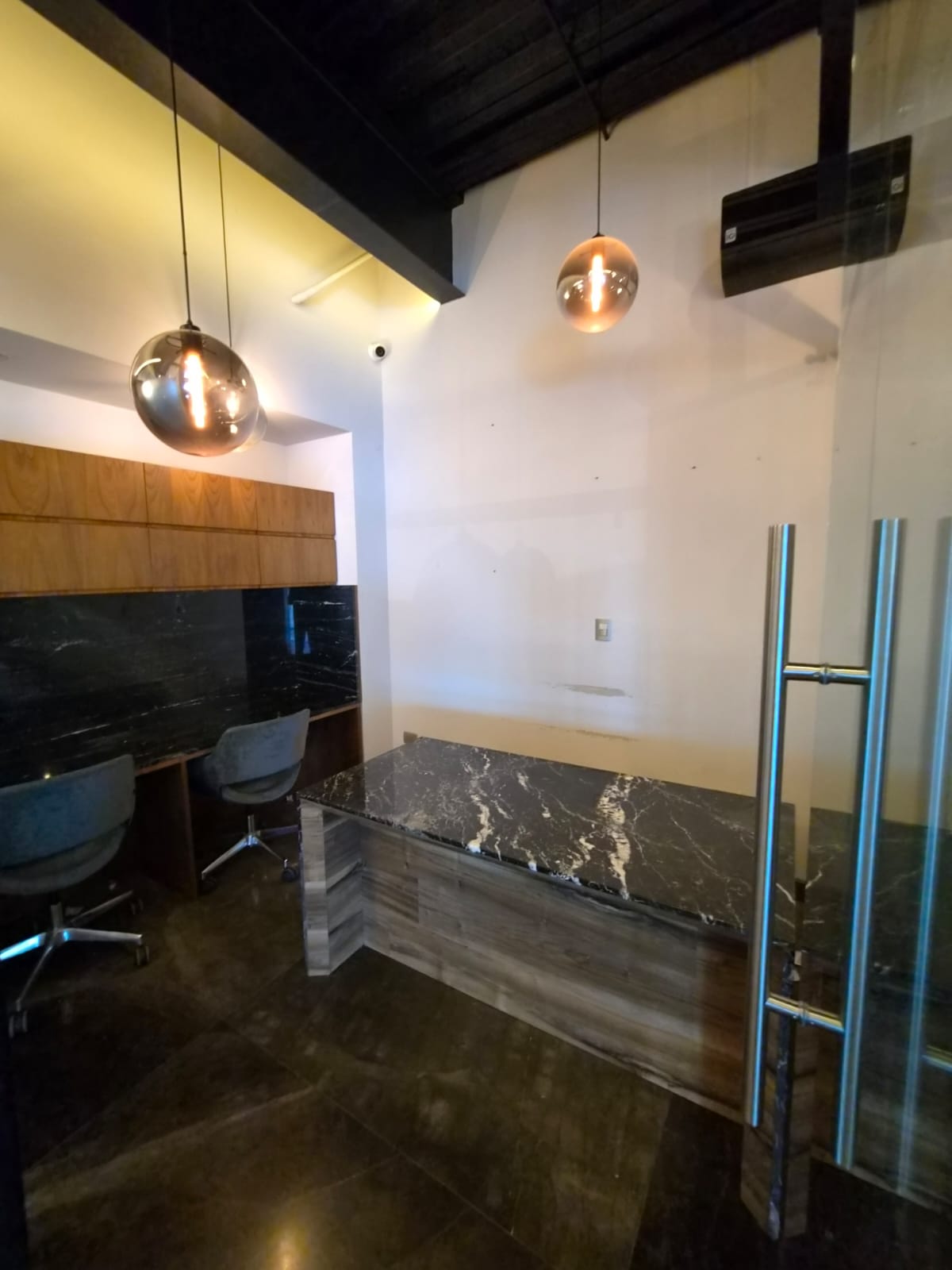 Office reception area with a marble-topped desk, two chairs, and glass entry door.