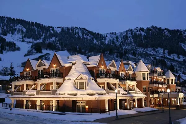 Snow-covered mountain residences with steep gabled roofs and a forested mountain backdrop.