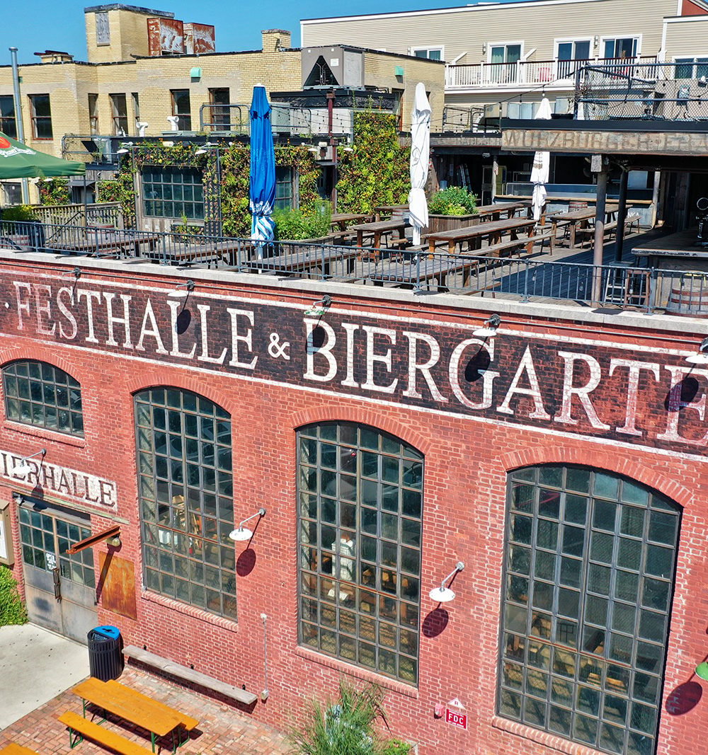 Red-brick commercial building with arched windows and a rooftop beer garden terrace.