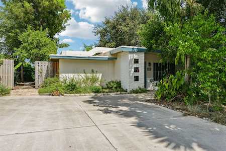 Single-story modern home with a flat roof and broad concrete driveway, framed by mature trees.