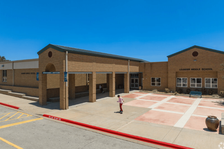 Leander Middle School with a brick facade, covered entrance, and paved courtyard.