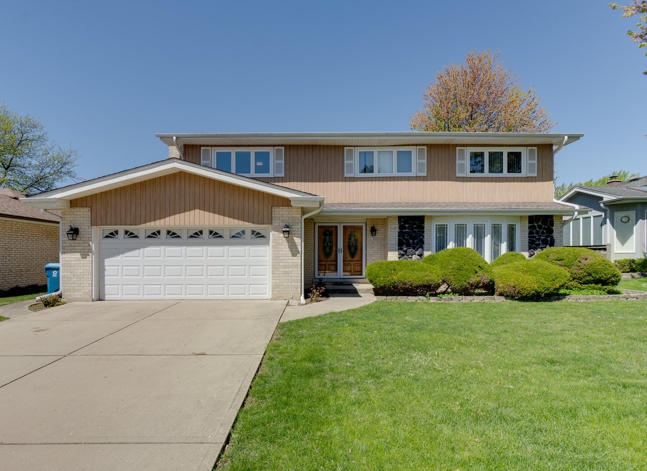 Two-story split-level home with a two-car garage, brick accents, and landscaped front lawn.