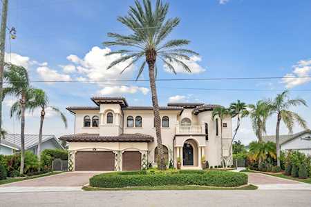 Cream stucco home with arched windows, two-car garage, and a tall palm tree in front.