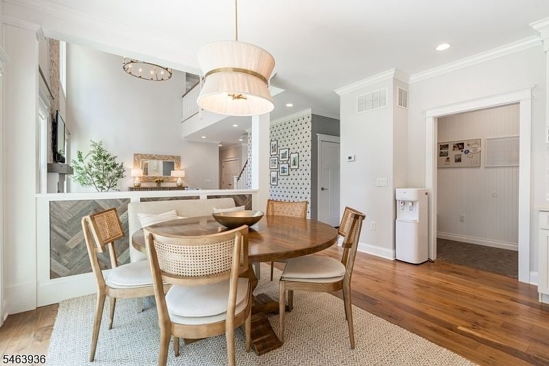 Dining area with a round wooden table, cane-back chairs, and a large pendant light.