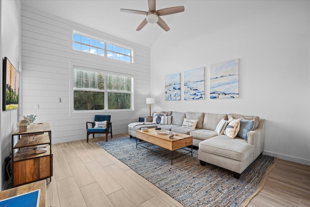 Furnished living room with a vaulted ceiling, tall windows, and a light sectional sofa.