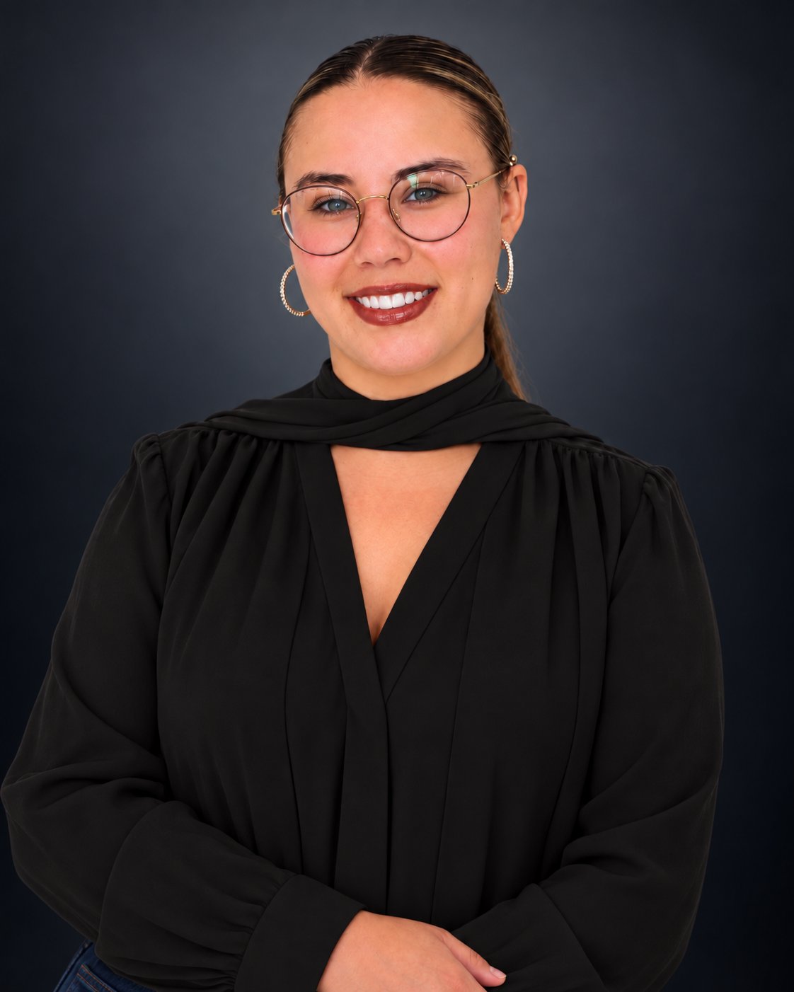 Ava Irizarry smiling in glasses and a black blouse against a dark studio backdrop.