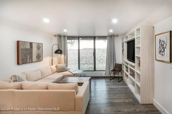 Living room with a cream sectional, built-in shelving, and sliding doors overlooking a snowy hillside.