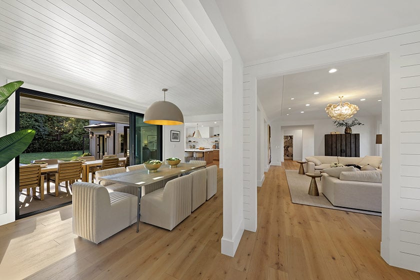 Staged dining and living area with sliding glass doors opening onto a garden patio.