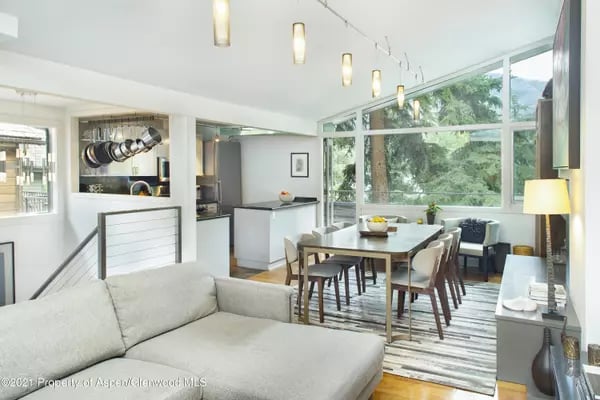 Open-plan living and dining area with large windows overlooking leafy trees.